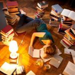 Young woman lying and sleeping on floor, surrounded by books --- Image by © Matthias Tunger/Corbis