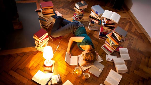 Young woman lying and sleeping on floor, surrounded by books --- Image by © Matthias Tunger/Corbis