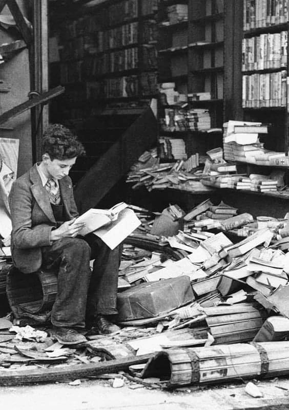 A boy sits reading in a bombed bookstore, London, on October 8, 1940.