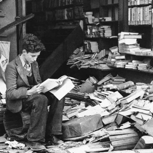 A boy sits reading in a bombed bookstore, London, on October 8, 1940.